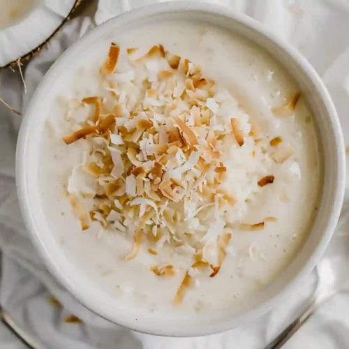Creamy homemade rice pudding recipe served warm in a rustic bowl, garnished with cinnamon and raisins.