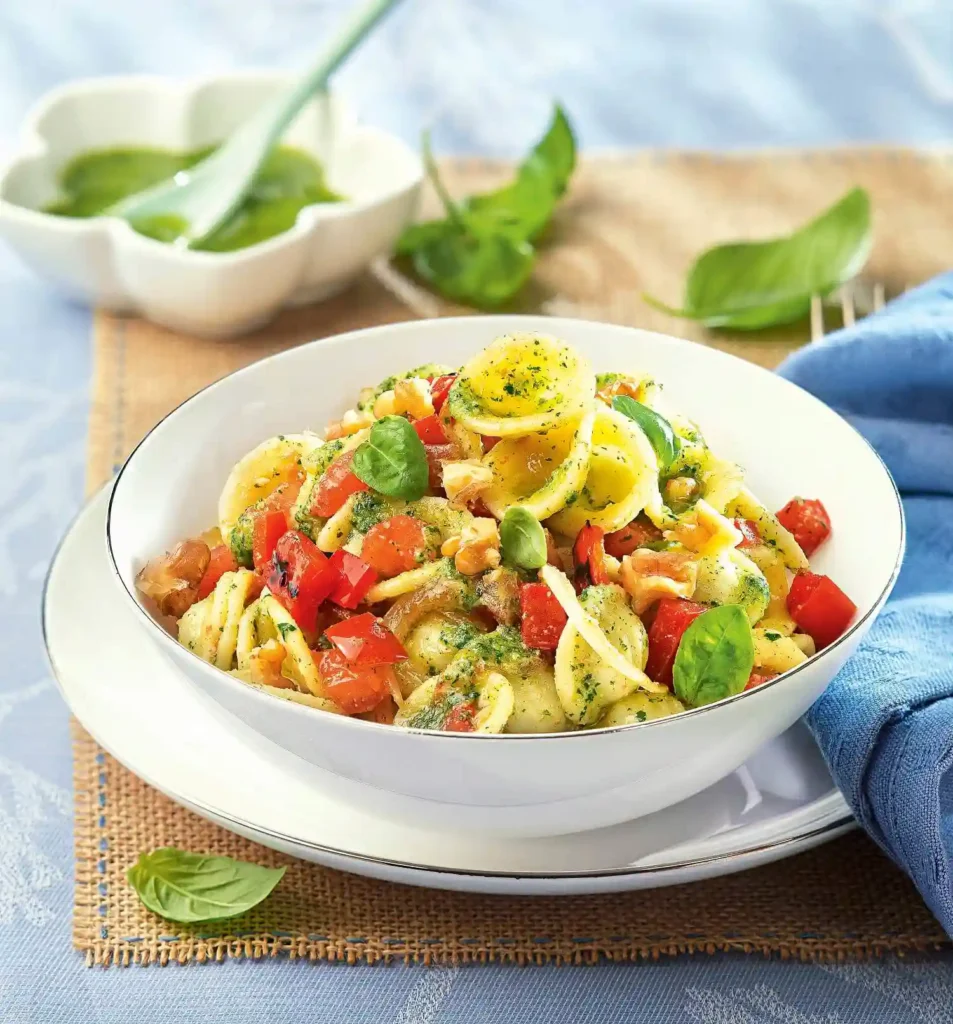Italian Bow Tie Pasta Salad Recipe A large glass or white ceramic bowl filled with colorful bow tie pasta salad, mixed with cherry tomatoes, cucumber, carrots, bell peppers, spinach