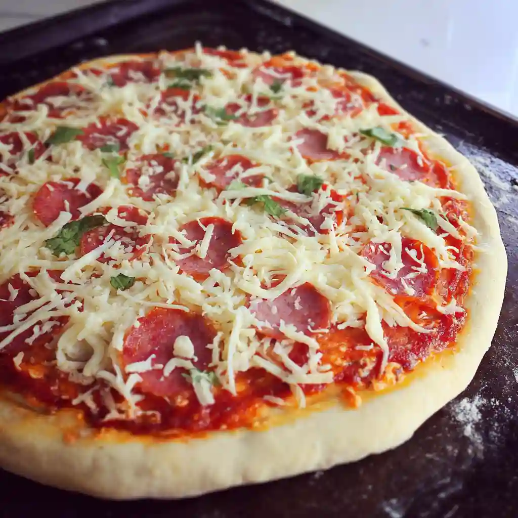 The Best Homemade Pizza Dough Recipe Rolling out homemade pizza dough with wooden rolling pin on floured surface ready for pizza making