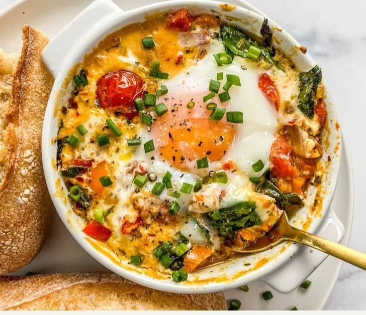 Baked feta eggs with tomatoes and spinach in a serving dish