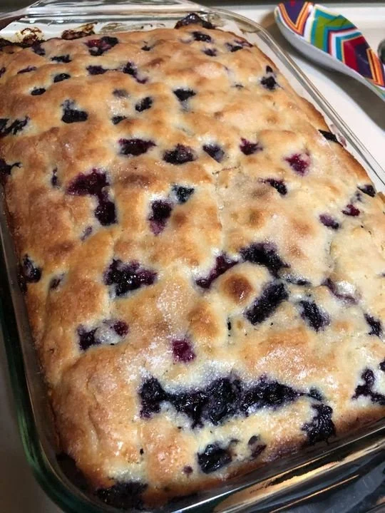 Delicious blueberry buttermilk cake served on a plate with fresh blueberries.