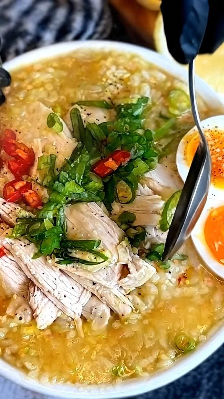 Bowl of Chicken Rice Porridge, a traditional Filipino congee topped with chicken and herbs.