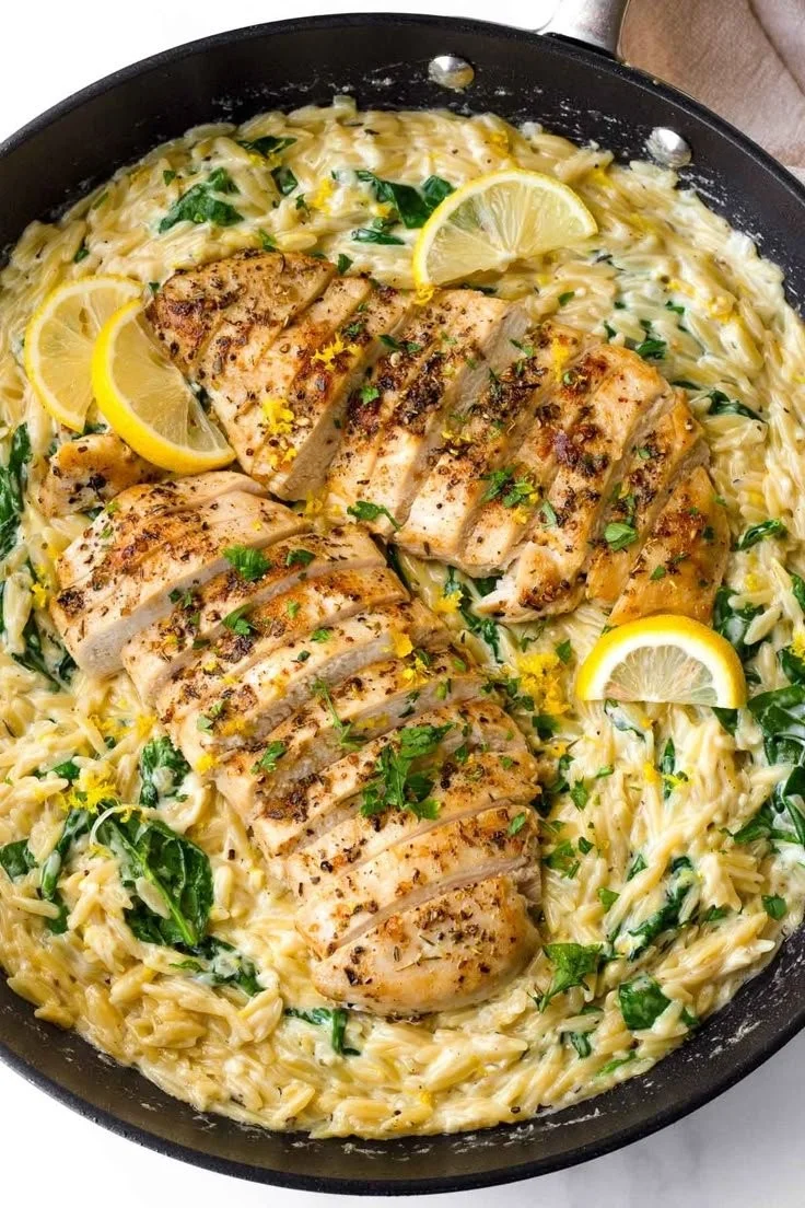 Creamy lemon chicken orzo dish served with herbs and lemon slices