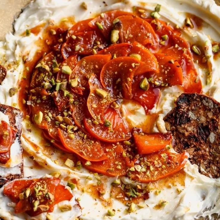 Whipped brie topped with caramelized persimmons served in a rustic dish.